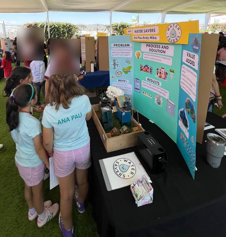 El equipo frente a su mampara y su maqueta en la feria